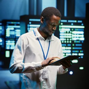 Technician in high tech facility walking through server rigs used for computationally intensive tasks such as molecular modeling or physical simulations. Specialist doing routine equipment maintenance